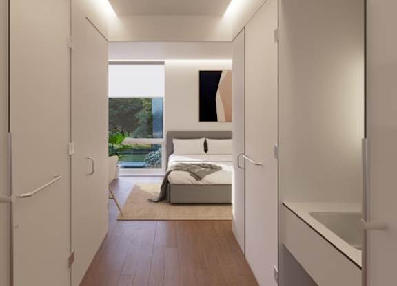 A white hallway with a bed and a window.
