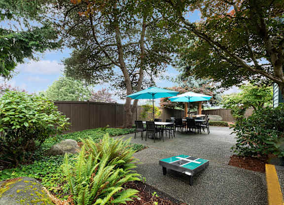 A backyard with a table and chairs under an umbrella.