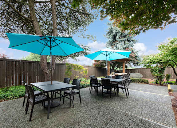 A table set up under a blue umbrella in a backyard.
