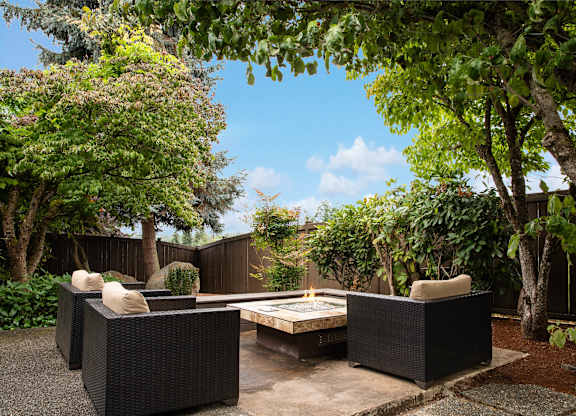 A patio with a table and chairs surrounded by trees.