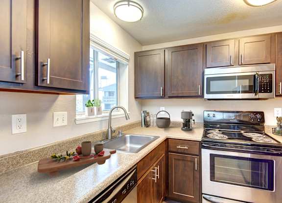 A kitchen with a sink, stove, and microwave.