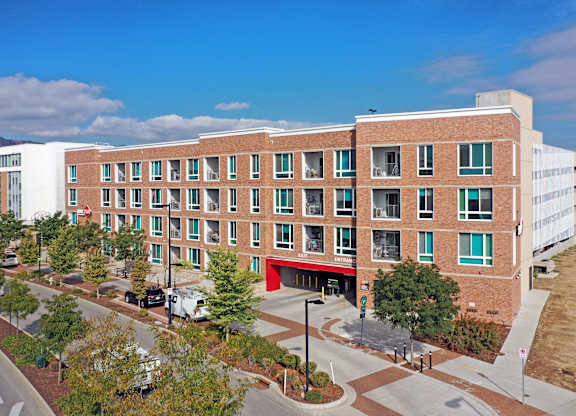 A large red brick building with a red awning sits in front of a parking lot at Depot Square in Boulder, CO