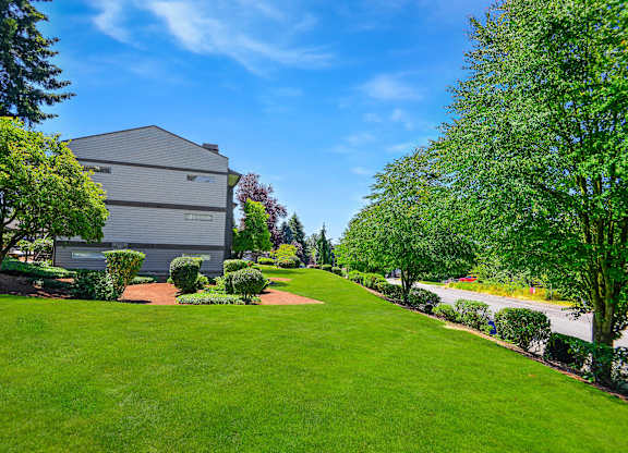 A well-maintained lawn leads to a grey building.