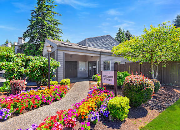 A garden with a Welcome Center sign in front of a building.