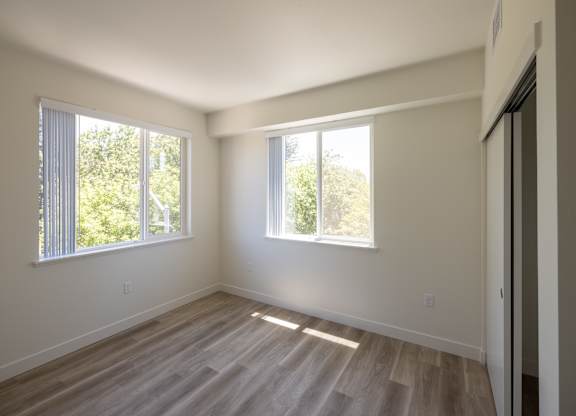 A room with wooden floors and two windows.