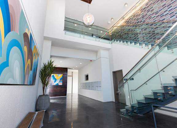 A hallway with a glass staircase and a colorful painting on the wall at View Point Apartments, Berkeley, CA, 94710