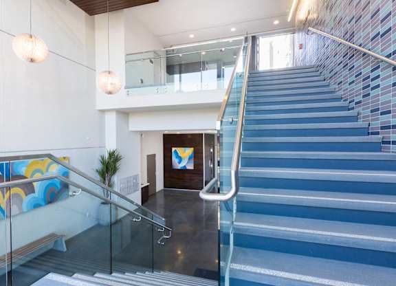 A staircase with a glass railing and a blue tiled wall at View Point Apartments, Berkeley California