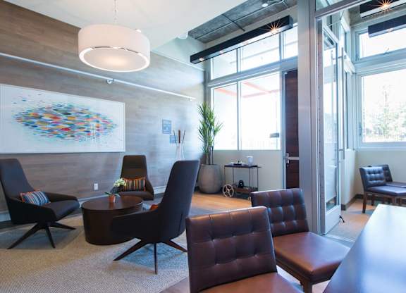 A modern living room with a large artwork on the wall and a variety of seating options at View Point Apartments, Berkeley, CA, 94710