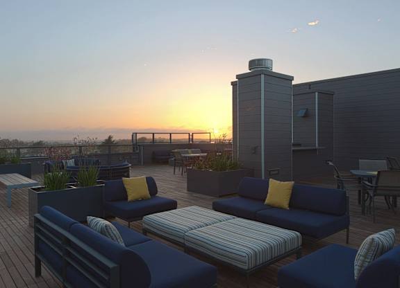 A sunset view of a rooftop patio with blue couches and tables at View Point Apartments, Berkeley, 94710