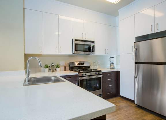 A modern kitchen with a stainless steel refrigerator and a white countertop at View Point Apartments, Berkeley