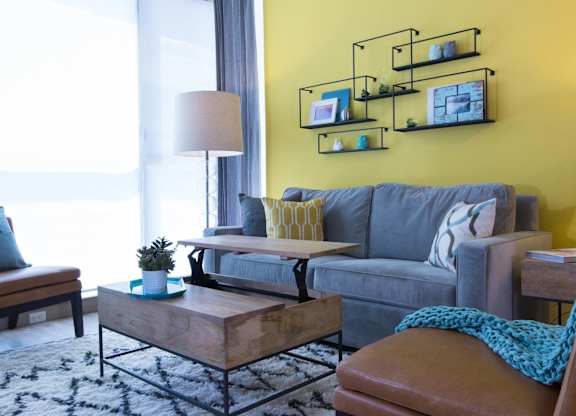 A living room with a grey couch, a wooden coffee table, and a yellow wall at View Point Apartments, Berkeley, CA, 94710