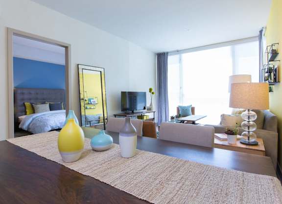 A well-lit bedroom with a large bed and a couch at View Point Apartments, Berkeley, 94710