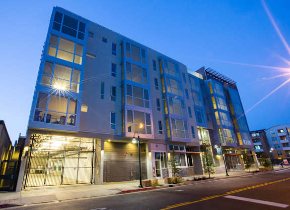A modern multi-story building with bright lights on at night at View Point Apartments,Berkeley