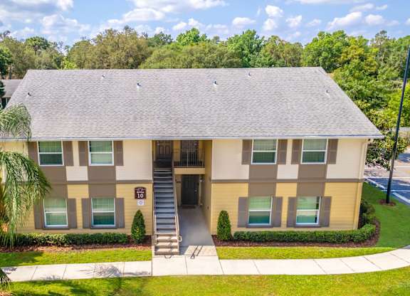 A two-story building with a beige and brown exterior and a grey roof at Academy on Dean Woods Apartments, Florida, 32825
