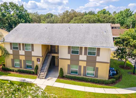 A two-story building with a beige facade and a grey roof at Academy on Dean Woods Apartments, Florida