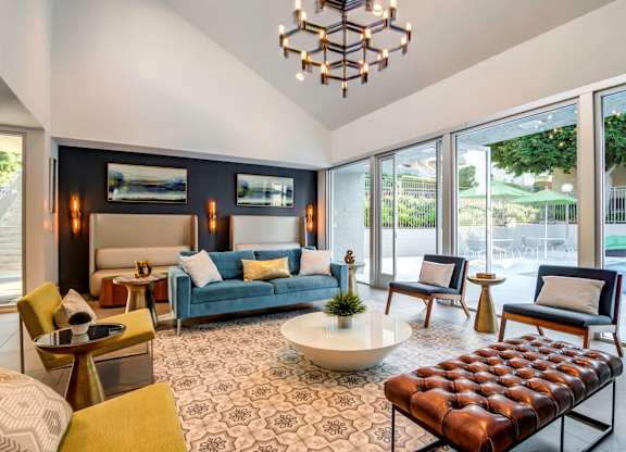 A living room with a blue couch and a brown leather ottoman.
