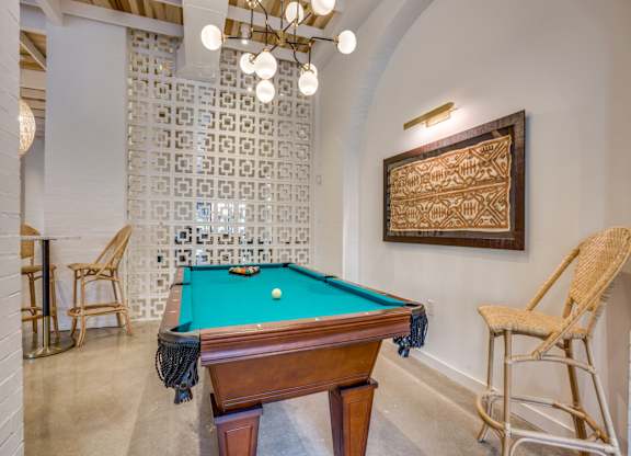 A pool table with a green cloth and a wooden frame is in the center of the room.