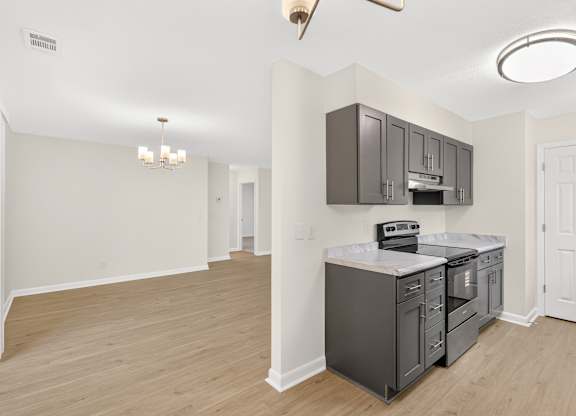 A kitchen with a white ceiling and a wooden floor.