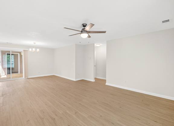 A spacious room with a ceiling fan and wooden flooring.