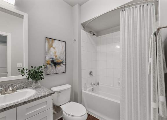 A white bathroom with a toilet, sink, and bathtub at CityWay Apartments, Indianapolis