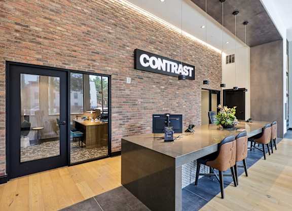 A modern office space with a brick wall and a long table with chairs.