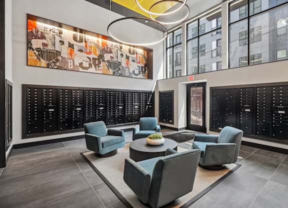 A modern waiting room with grey chairs and a large artwork on the wall.