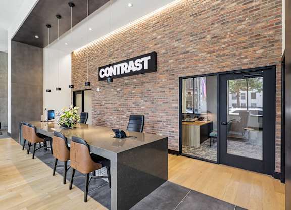 A room with a long table and chairs with a brick wall and a sign that says Contrast.
