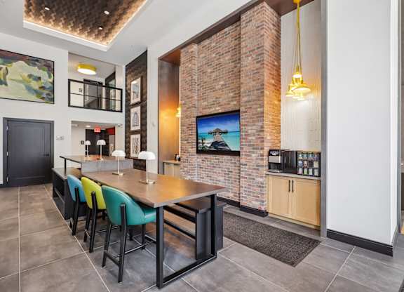 A modern kitchen with a brick wall and a long table.