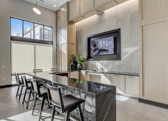 a kitchen with a bar with chairs and a tv on the wall