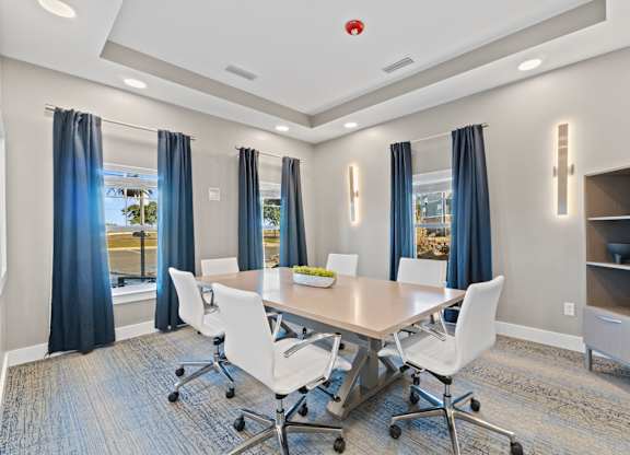 A conference room with a table, chairs, and a window with curtains.