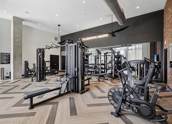 A gym with a variety of equipment including a treadmill, weights, and a bench.