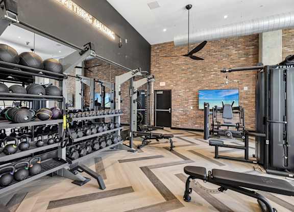 A gym with a variety of equipment including weights and a bench press.
