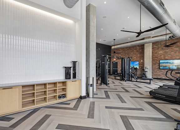 A gym with a variety of equipment including treadmills and weights.