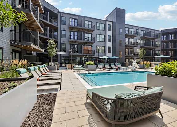 A modern poolside lounge area with a sunbed and a pool.
