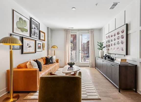 Stylish living area at Contrast OTR in Over-the-Rhine, Cincinnati featuring leather sofa, curated artwork, and natural light from French doors.