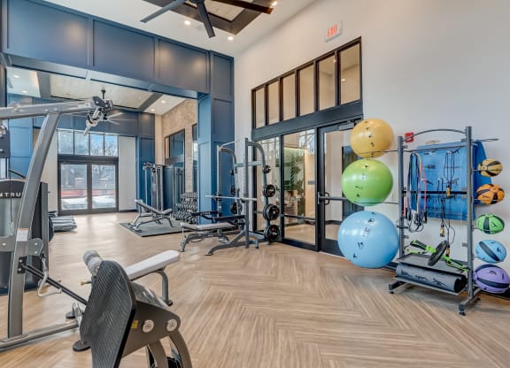 a gym with cardio equipment and weights on the floor and glass doors