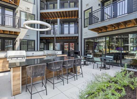 A modern outdoor kitchen with a bar and chairs.