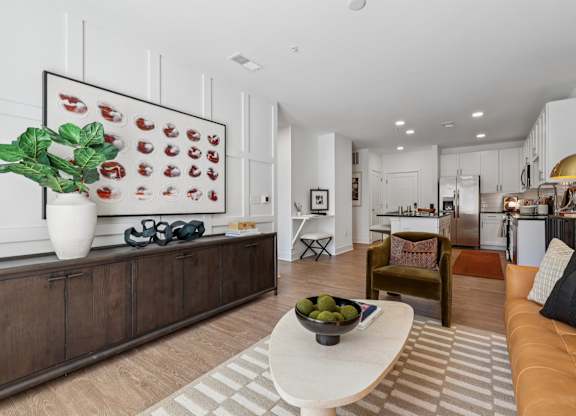 Open living and kitchen space at Contrast OTR in Cincinnati, OH showcasing designer finishes, white cabinetry, and wood-style flooring.