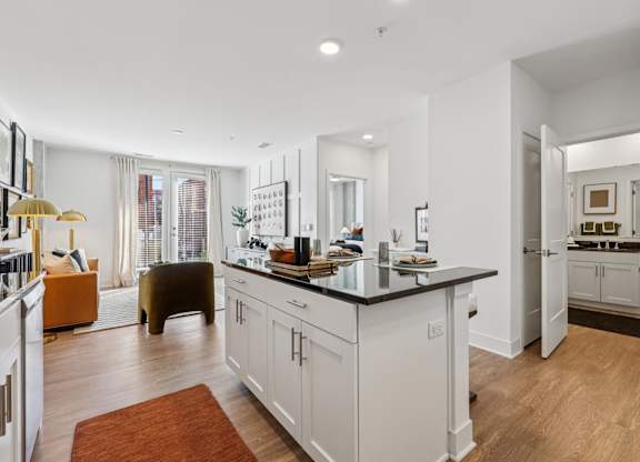 A modern kitchen with white cabinets and a black countertop.