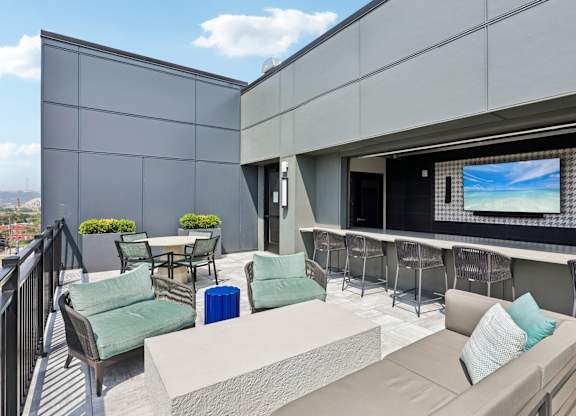 A balcony with a table, chairs, and a television.