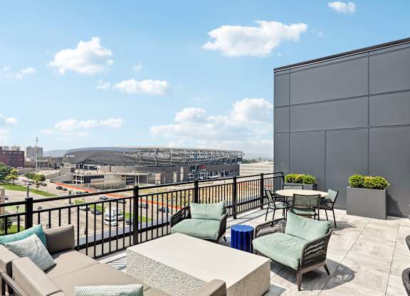 A balcony with a table and chairs overlooking a parking lot and buildings.