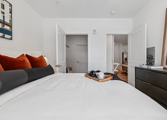 Bright bedroom at Contrast OTR in Cincinnati, OH with green accent decor, modern artwork, and soft lighting.