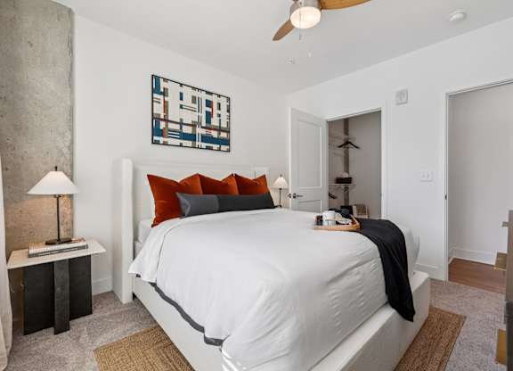 Bedroom at Contrast OTR in Cincinnati, OH with mid-century modern decor, wood nightstand, and bright window views.