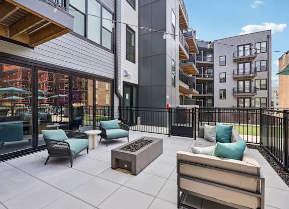 A patio area with a table and chairs is surrounded by a black fence.