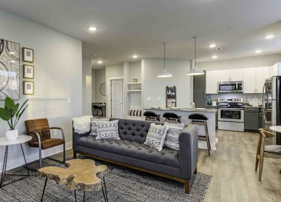 a living room with a couch and a kitchen in the background at Echo Park at Perry Crossing Apartments, Indiana, 46168