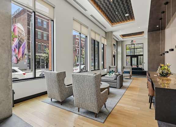 A modern office lobby with a wooden floor and grey chairs.
