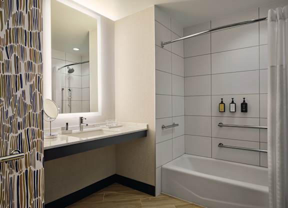A bathroom with a white tub and a sink with a mirror.
