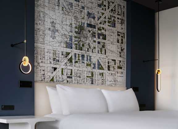 A bedroom with a large map on the wall and a bed with white pillows.