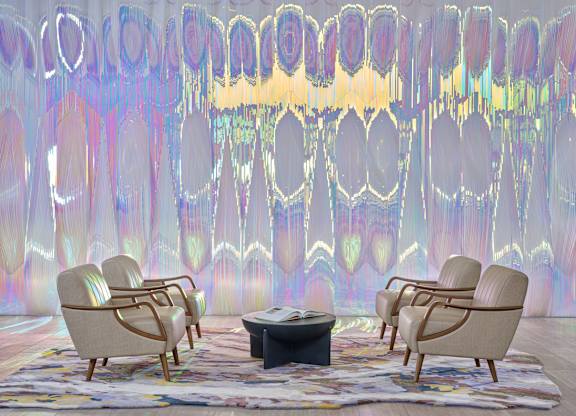 A room with a table and chairs in front of a wall with a colorful pattern.