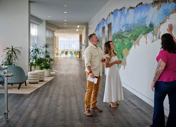 A man and woman are painting a mural on a wall.